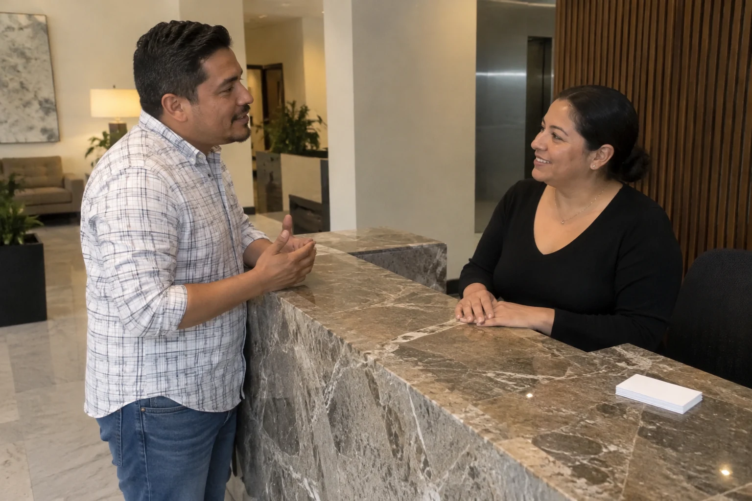 Una mujer y un hombre conversan junto a la recepción de un edificio.