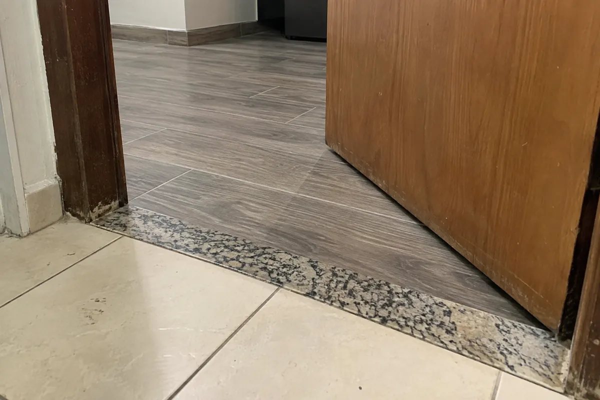 Vista baja de una puerta abierta y la transición entre dos tipos de piso