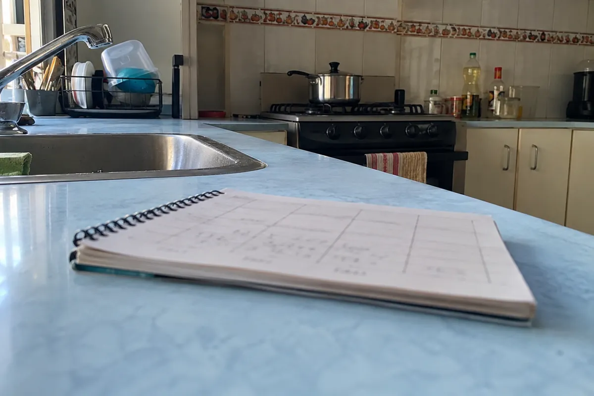 Libreta abierta con una cuadrícula sobre una cubierta azul de cocina