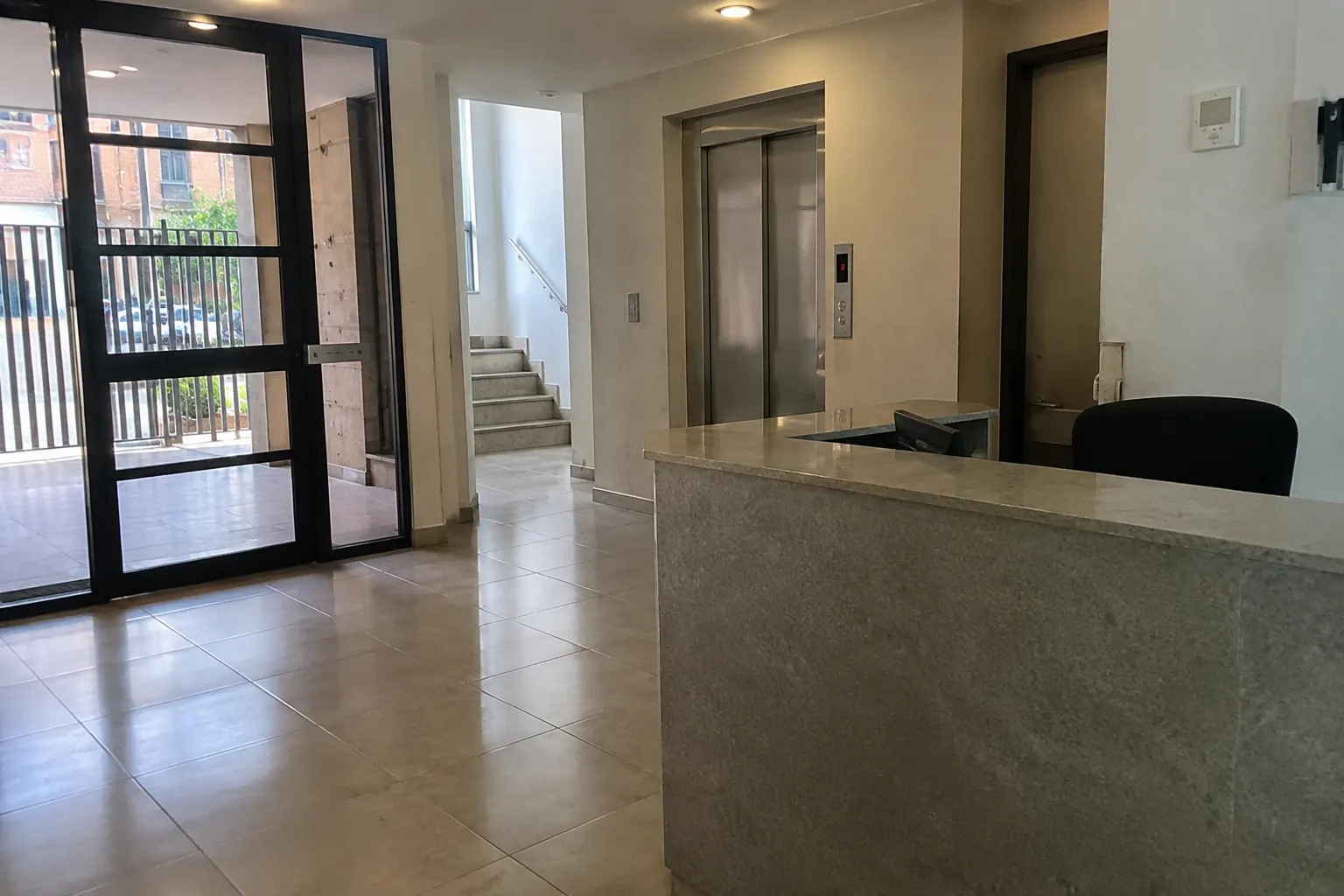 Entrada y recepción vacías de un edificio, con elevador y espacio libre de paso