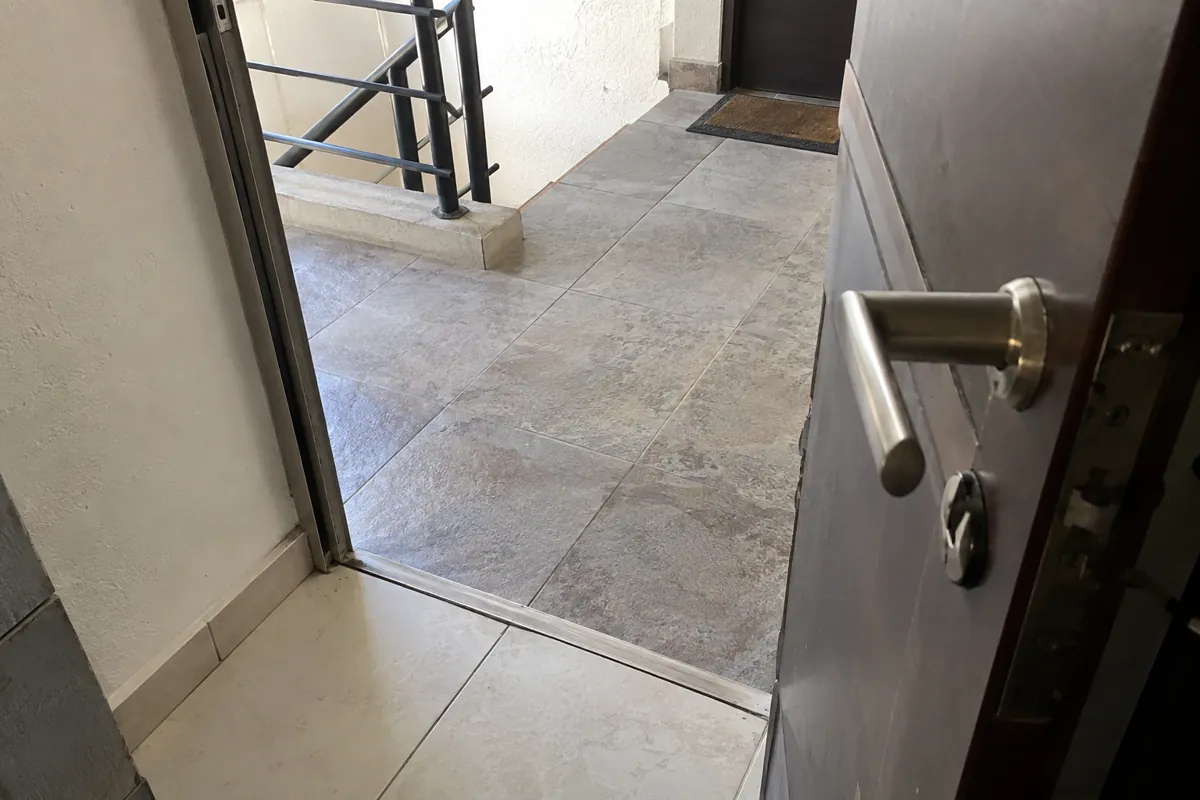 Puerta abierta con manija metálica y umbral que comunica con un pasillo