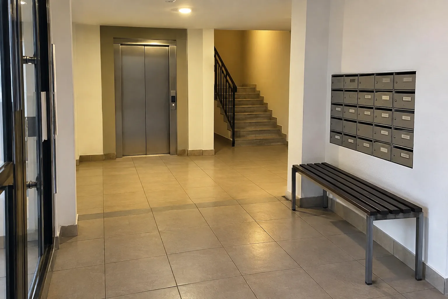 Vestíbulo vacío con una banca, buzones, elevador y un recorrido despejado