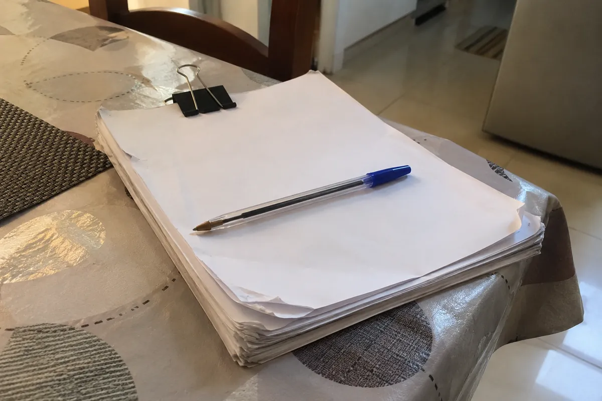 Bolígrafo azul sobre un conjunto de hojas sujetas con una pinza metálica