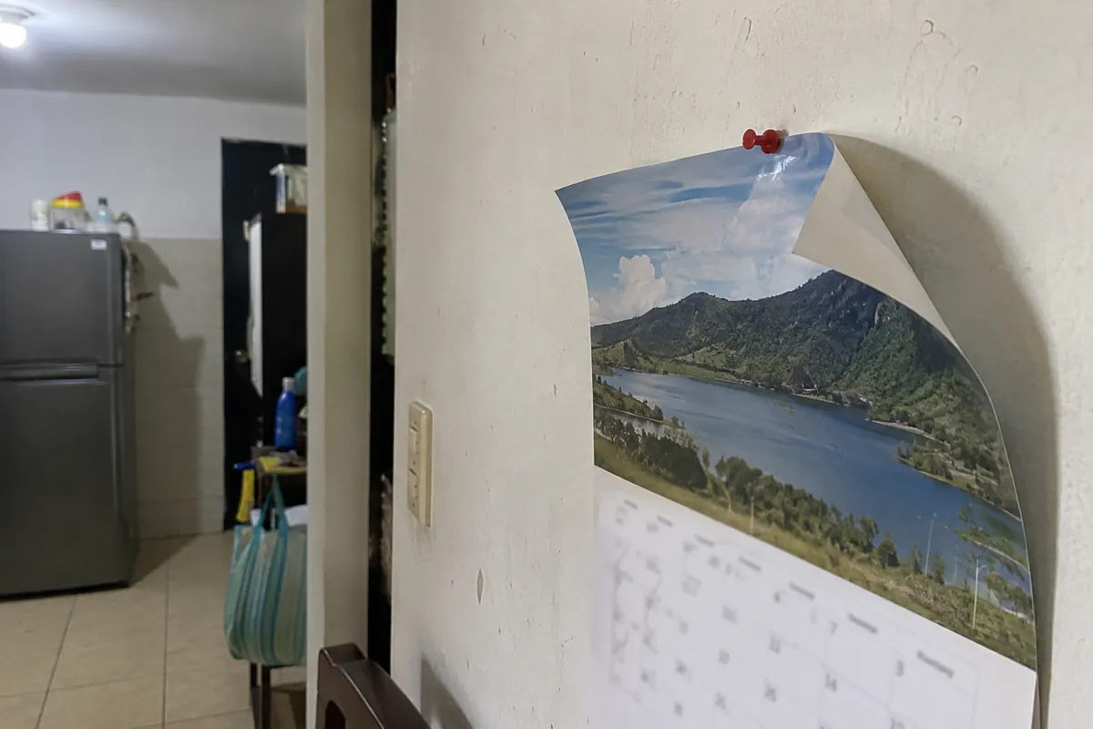 Calendario de pared con una esquina doblada y una tachuela roja junto a una puerta