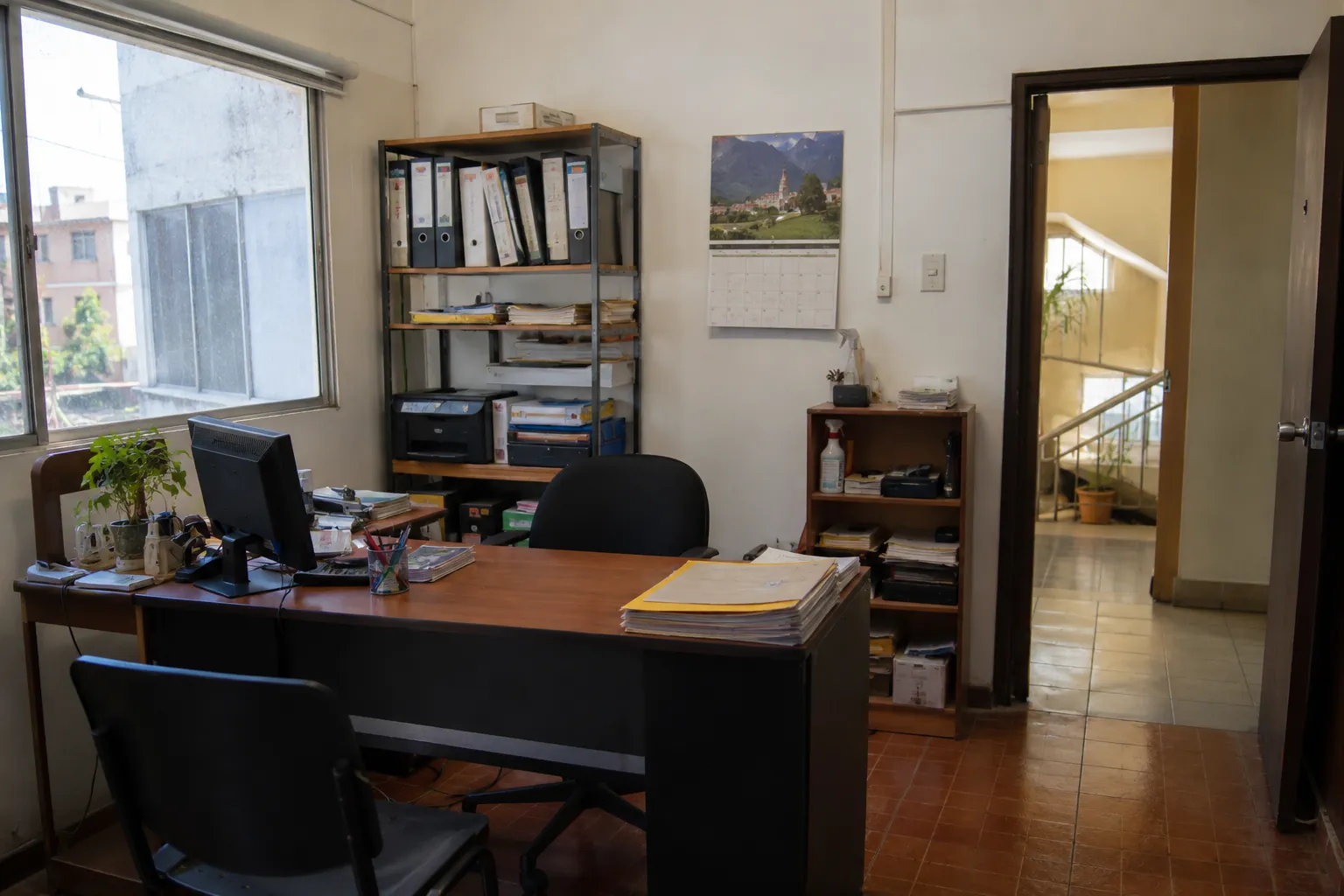 Oficina con calendario de pared, archivadores y documentos sobre el escritorio
