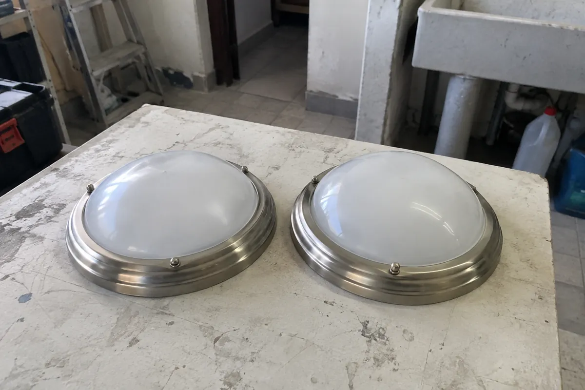Dos luminarias redondas apagadas sobre una mesa de trabajo desgastada