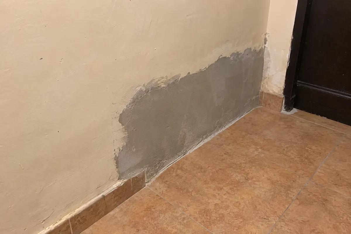 Parche de mortero sin pintar en la parte baja de una pared junto a una puerta