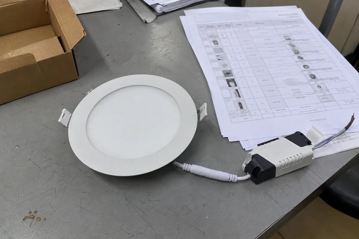 Luminaria circular desconectada junto a documentos sobre una mesa gris desgastada