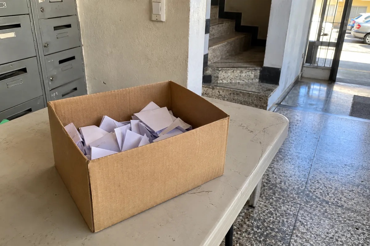 Caja de cartón con papeles doblados sobre una mesa cerca de los buzones y la entrada