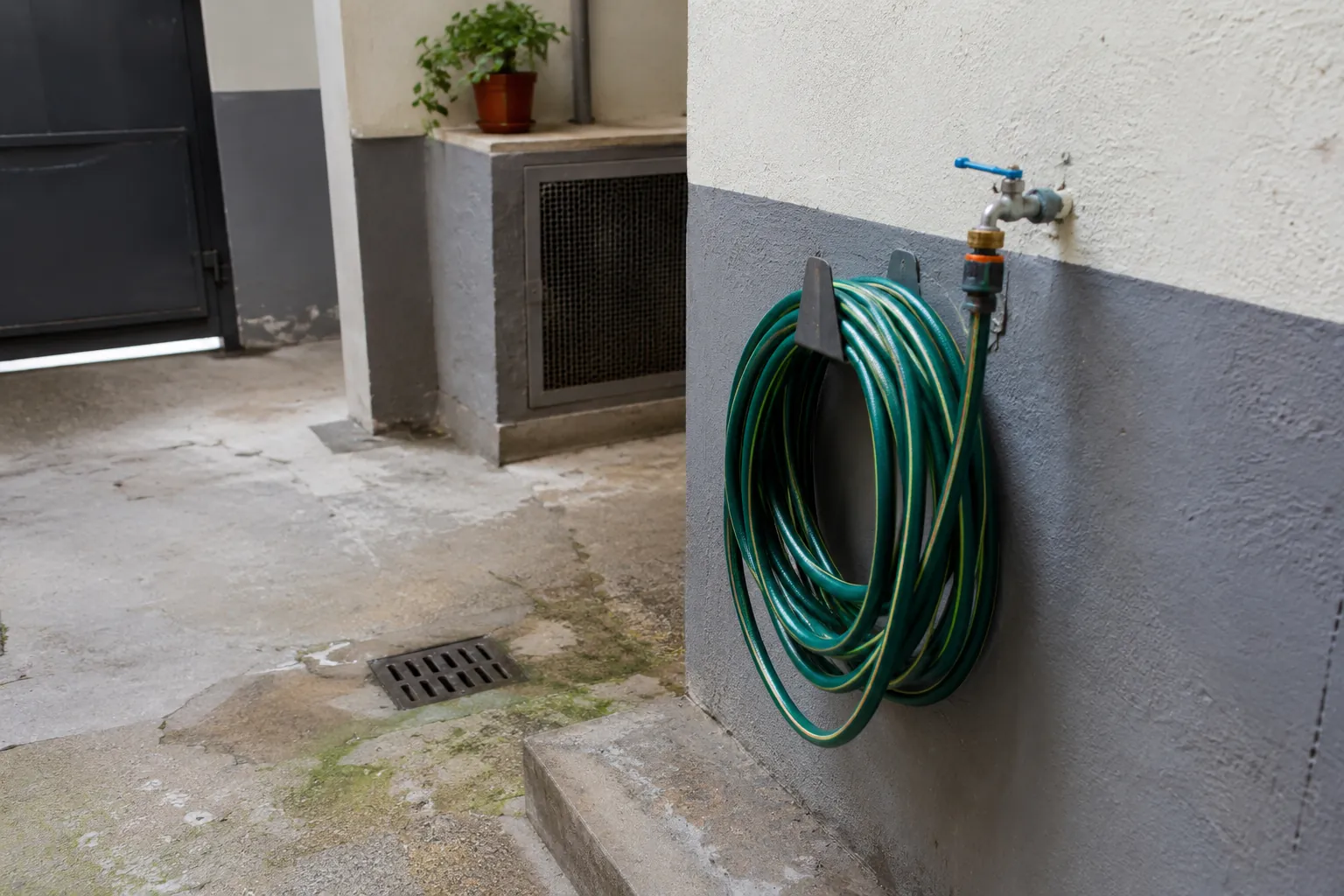 Manguera enrollada conectada a una llave de agua en un patio residencial