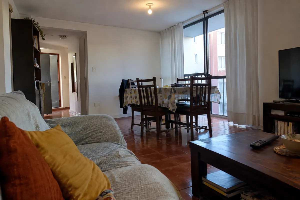 Sala vacía con sofá, mesa, sillas y una ventana amplia