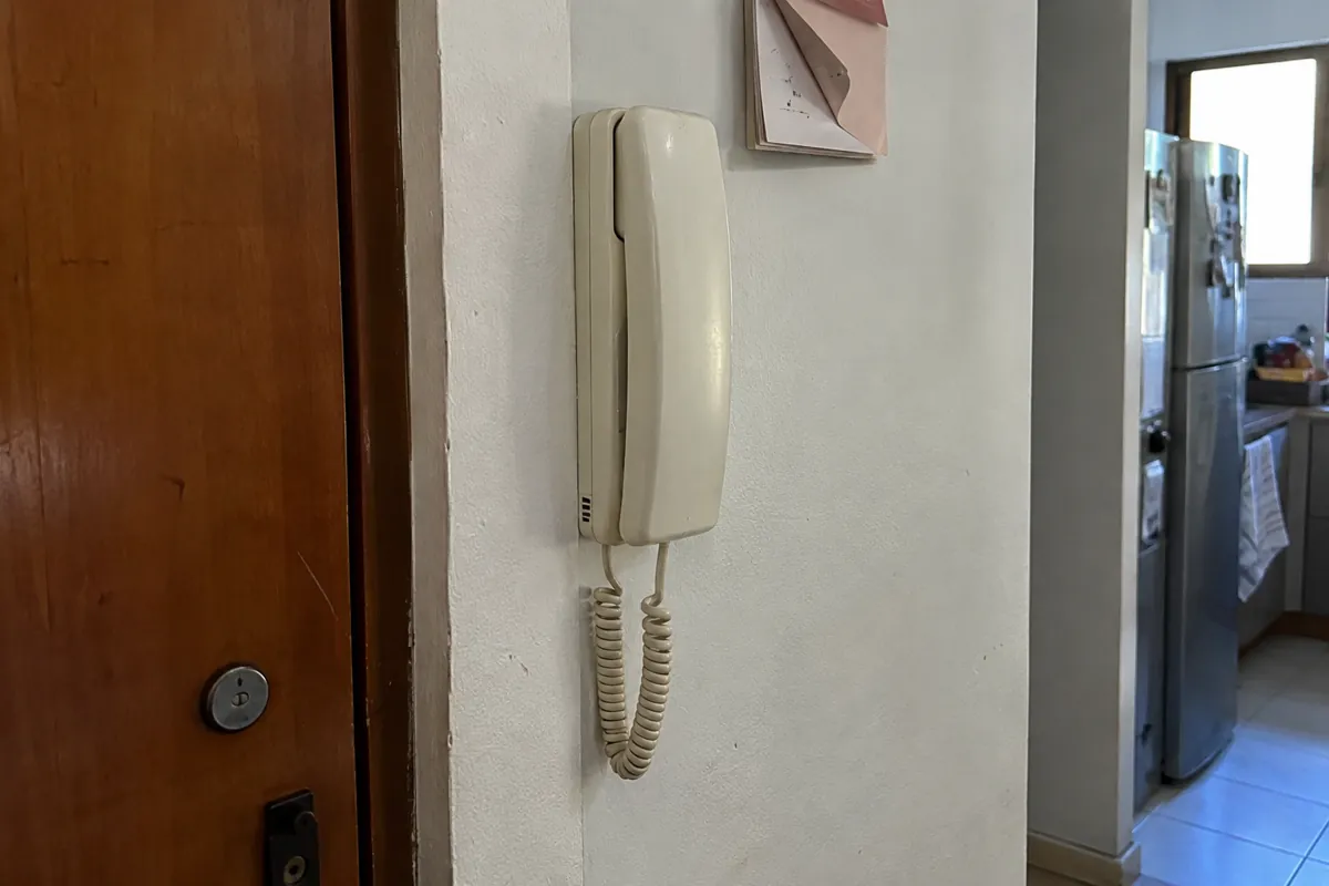 Auricular de pared con cable en espiral junto a unas hojas con una esquina doblada