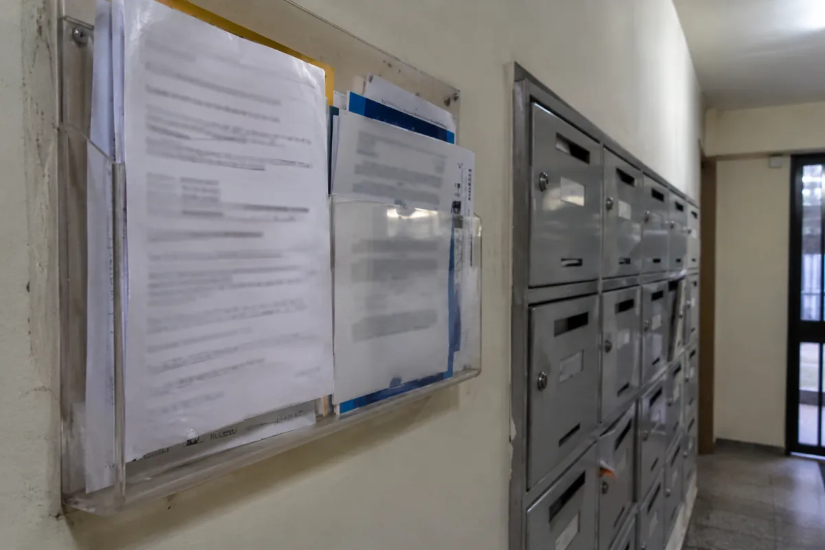 Portadocumentos transparente en la pared junto a una fila de buzones metálicos