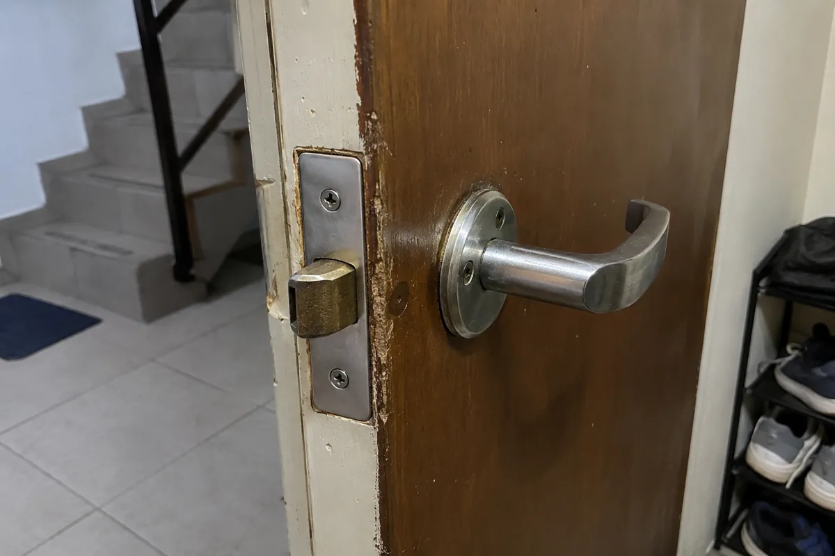 Detalle de la manija metálica y el pestillo de una puerta entreabierta