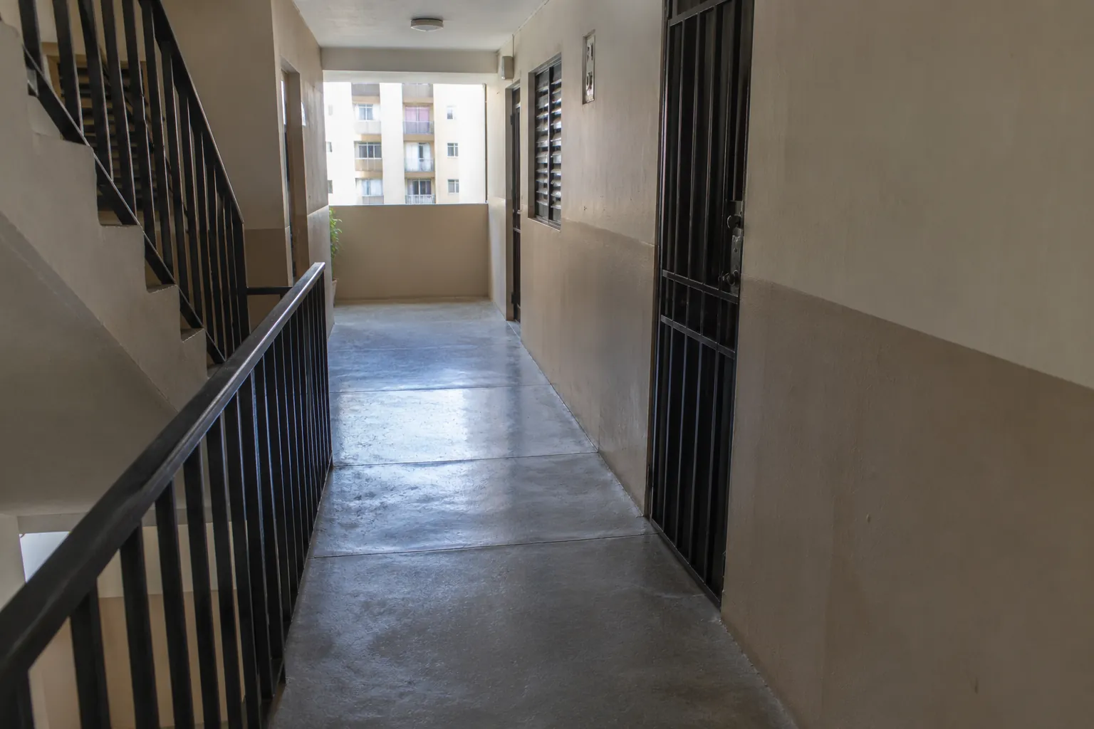 Pasillo residencial despejado con paredes de dos tonos y barandal metálico