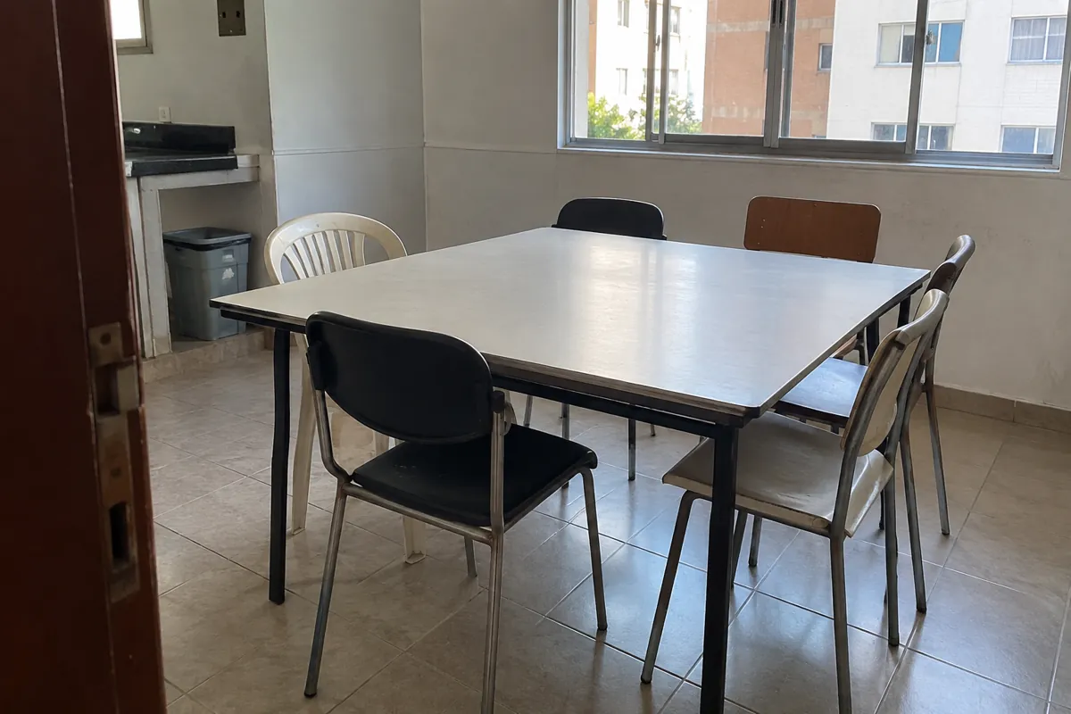 Mesa despejada con sillas diferentes en un salón junto a una ventana