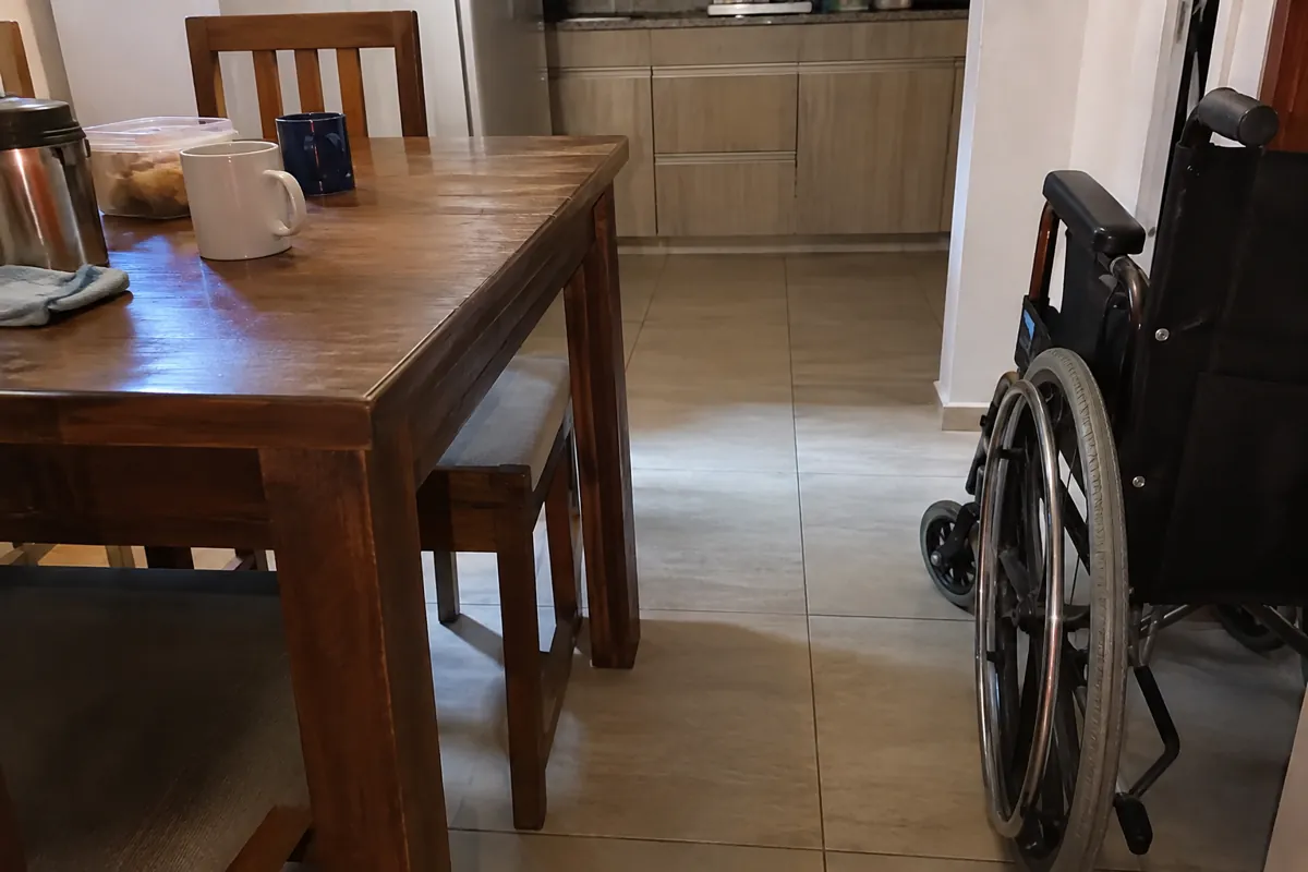Una silla de ruedas está junto a una mesa con tazas en una habitación