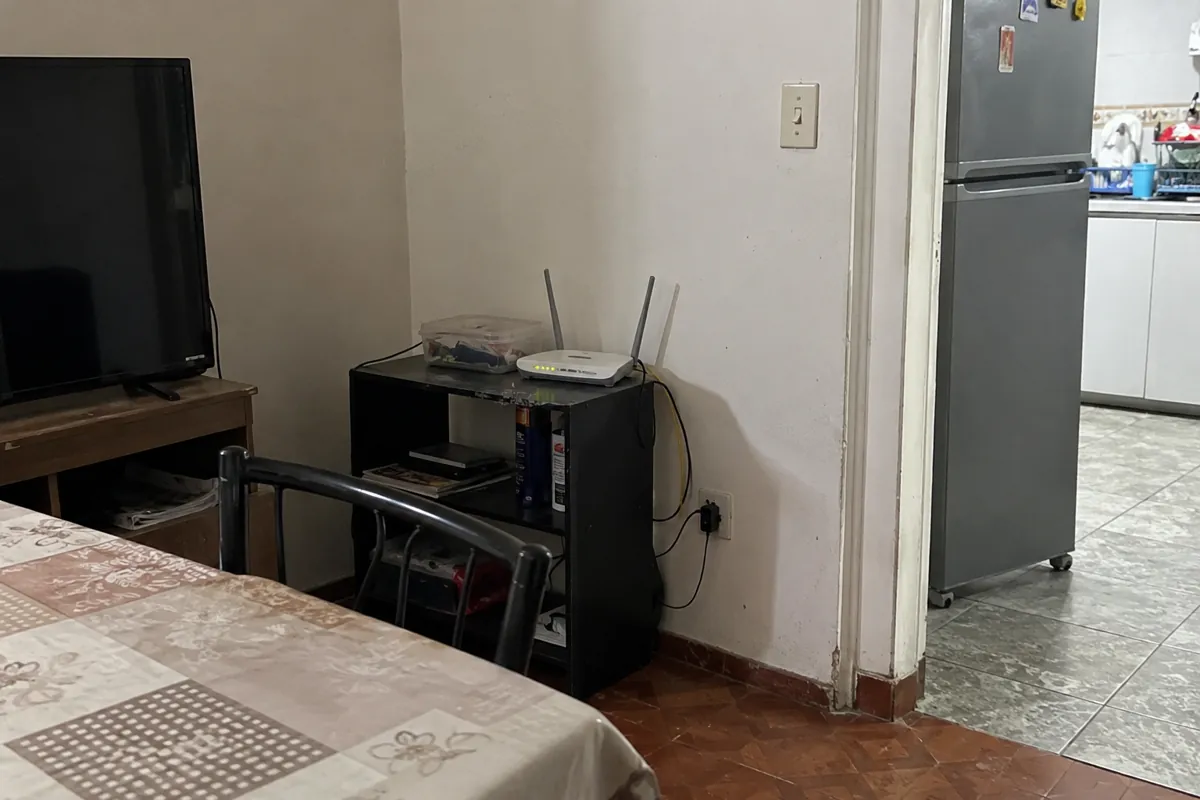 Router con antenas y luces encendidas sobre un mueble junto a un televisor