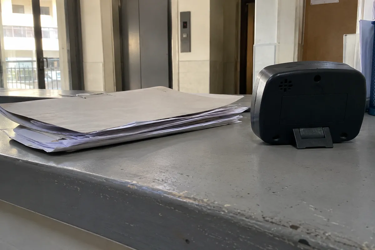 Hojas apiladas y parte posterior de un reloj de escritorio sobre un mostrador