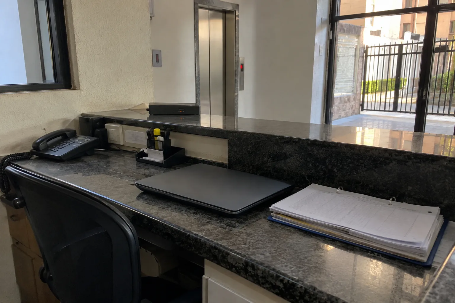 Computadora portátil cerrada y carpeta con documentos sobre el escritorio de una recepción vacía