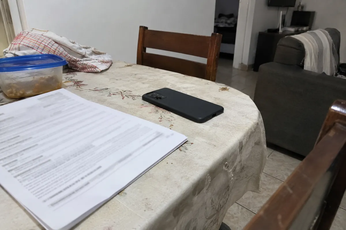 Teléfono boca abajo junto a unas hojas impresas sobre una mesa con mantel