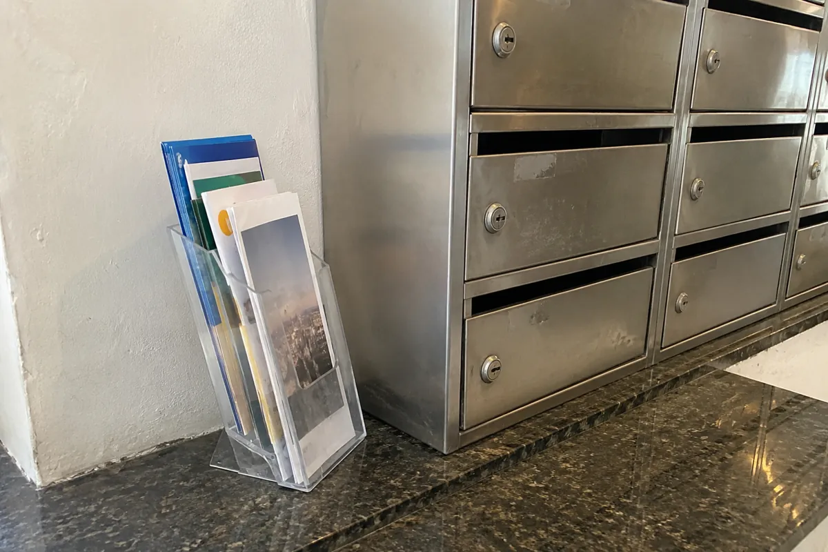 Folletos en un exhibidor transparente junto a buzones metálicos