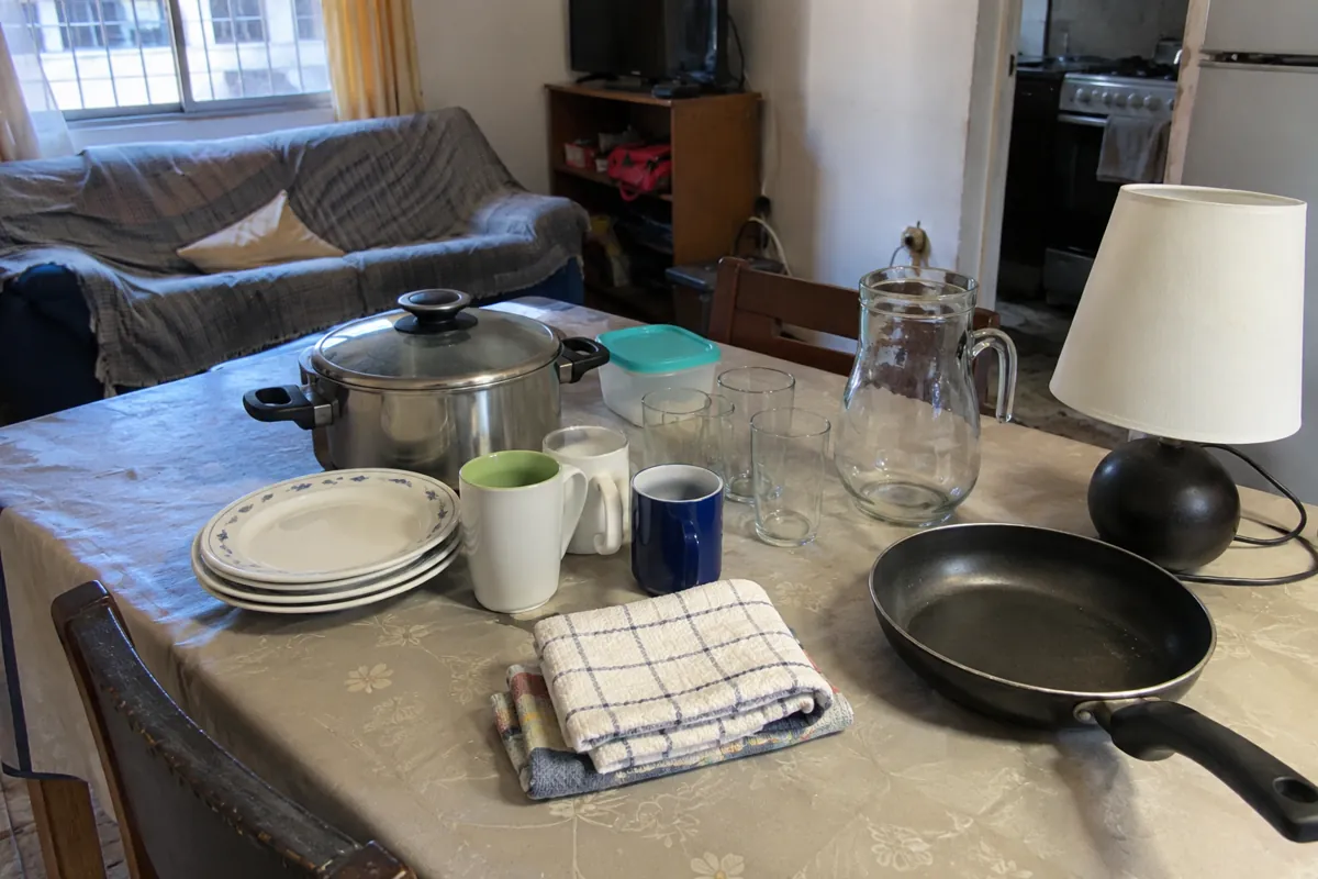 Olla, platos, vasos, tazas, una lámpara y otros objetos domésticos sobre una mesa