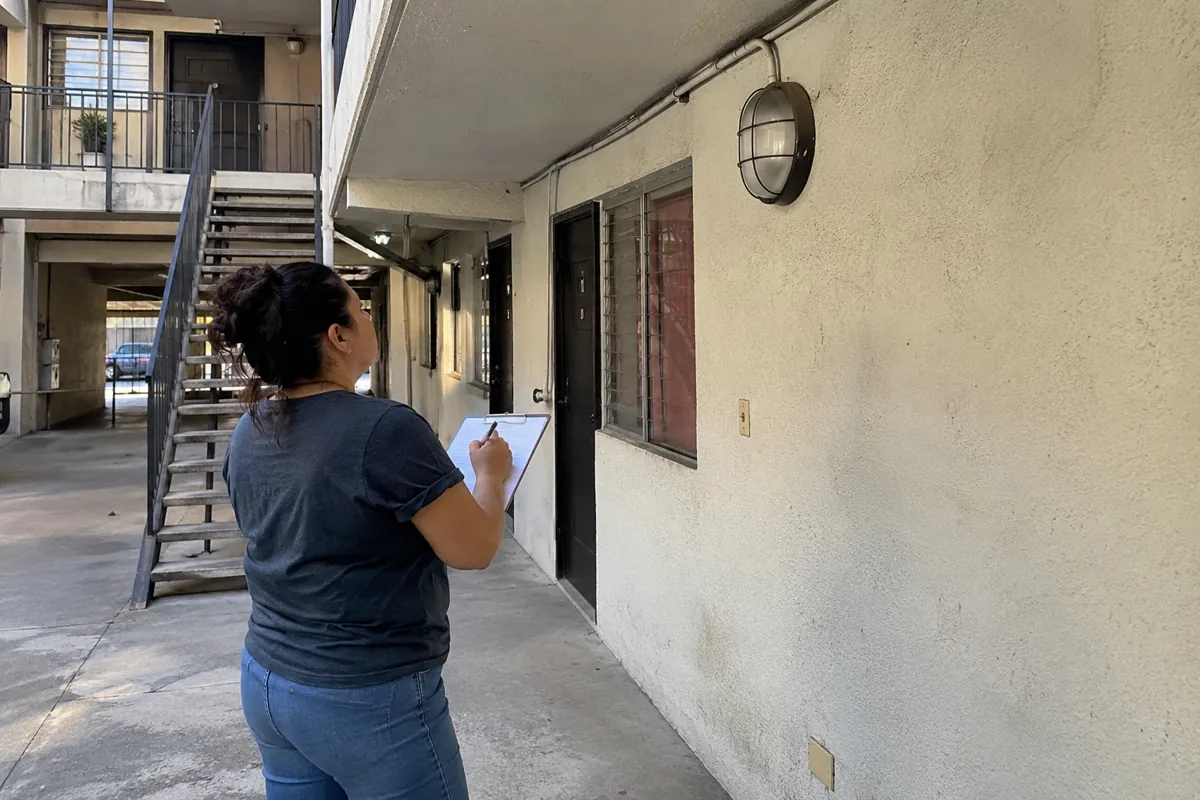 Una mujer observa una lámpara de pared y toma notas en un portapapeles