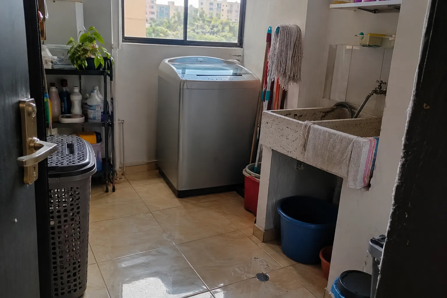 Cuarto de lavado con lavadora, lavadero, trapeador y productos de limpieza