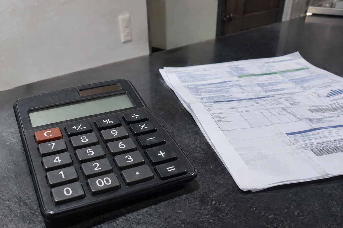 Calculadora usada junto a varias hojas impresas sobre un mostrador oscuro
