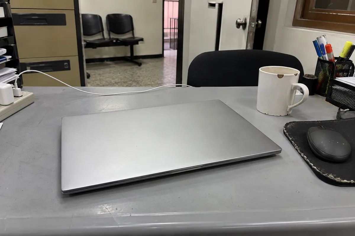 Computadora portátil cerrada junto a una taza y un ratón sobre un escritorio