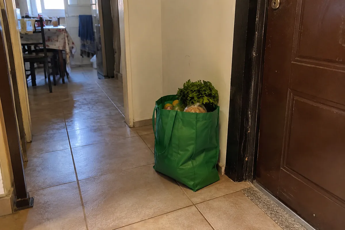 Bolsa reutilizable con alimentos colocada junto a una puerta en un pasillo
