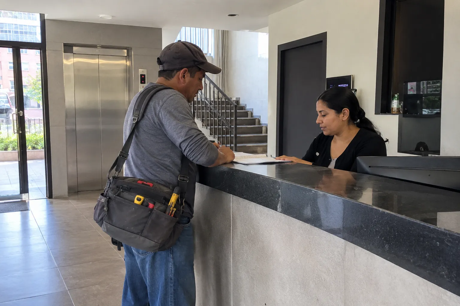Un hombre con bolsa de herramientas revisa un cuaderno en el mostrador mientras una mujer lo atiende