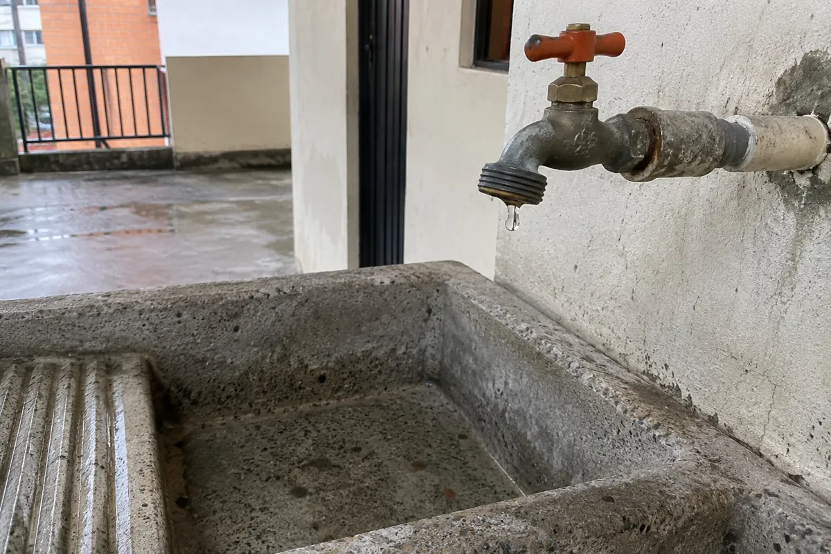 Gota de agua en una llave sobre un lavadero de concreto