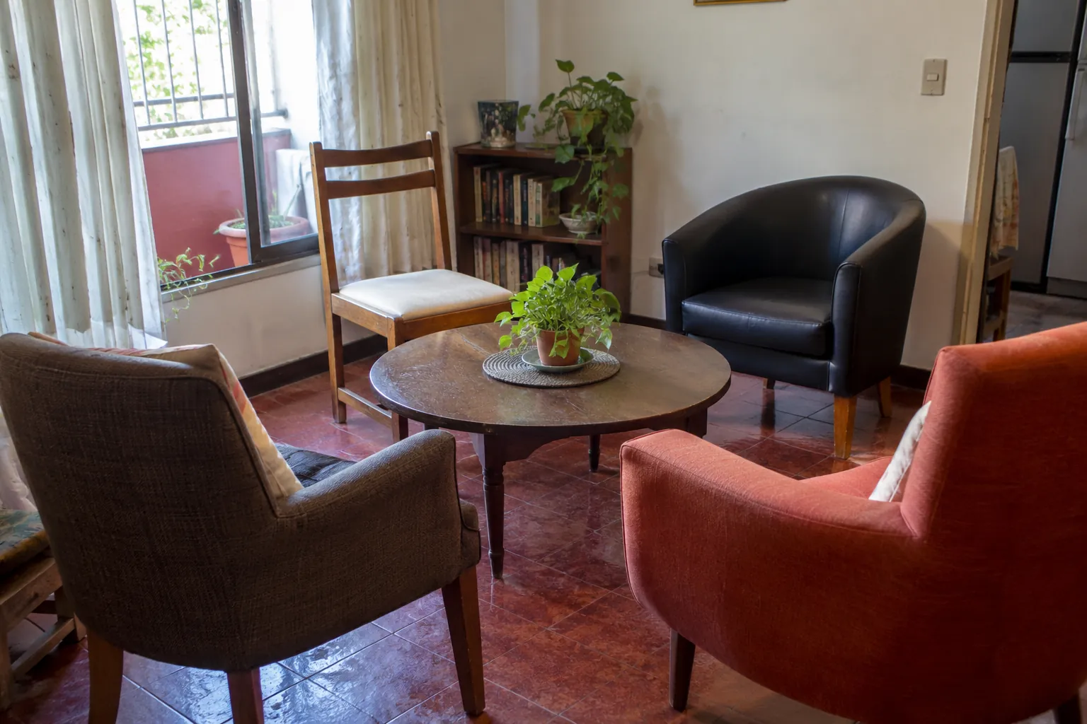 Tres sillones y una silla de madera alrededor de una mesa redonda