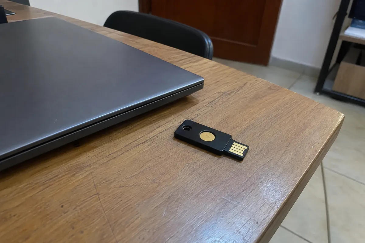 Una llave de seguridad USB negra está junto a una computadora portátil cerrada