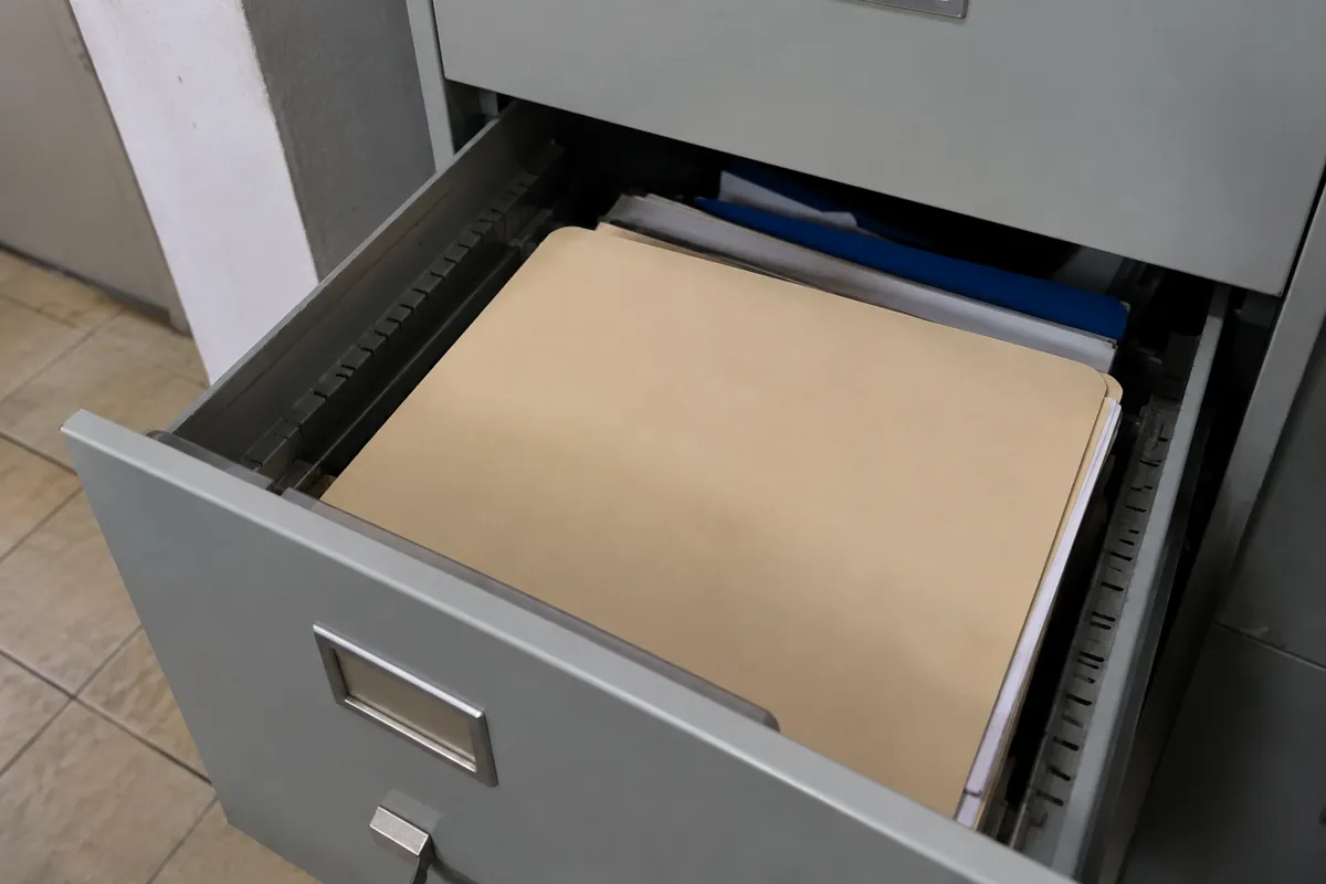 Carpetas con documentos guardadas en un cajón metálico abierto