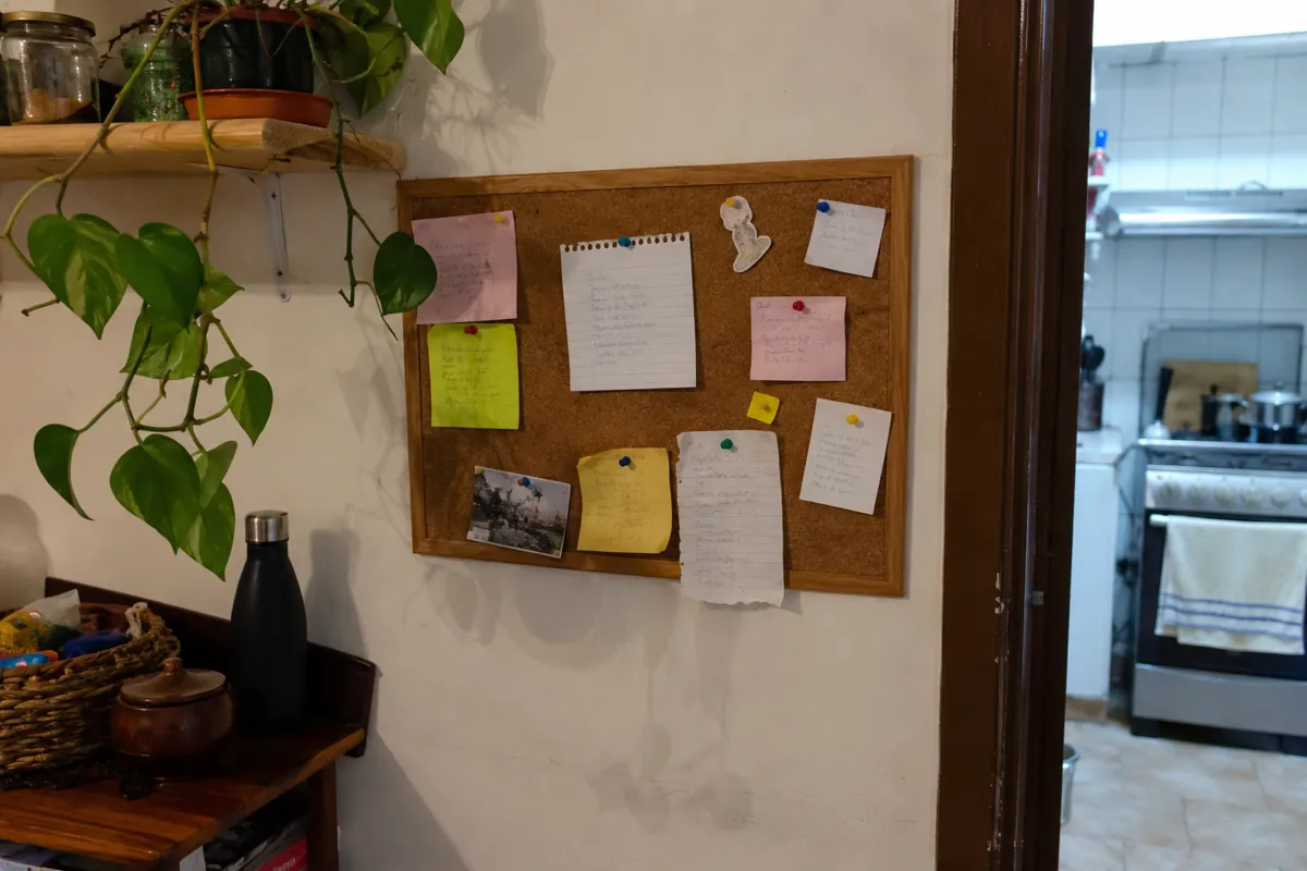 Tablero de corcho con notas sujetas con tachuelas junto a la entrada de una cocina