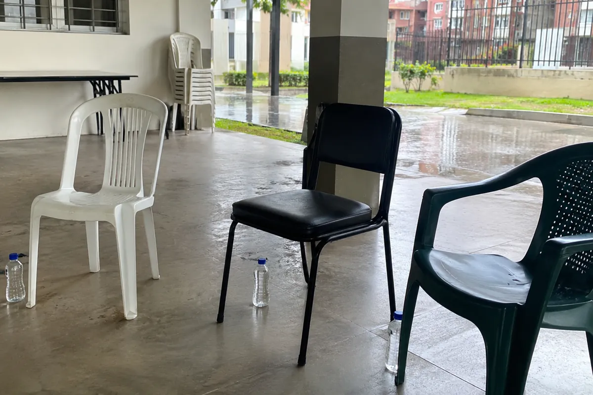 Tres sillas vacías con botellas de agua en un salón abierto hacia el patio