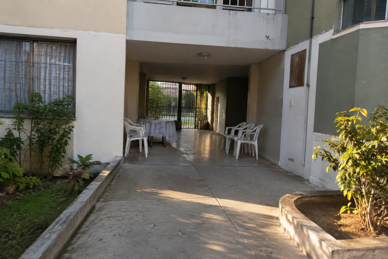 Sillas y una mesa junto al acceso de un edificio residencial
