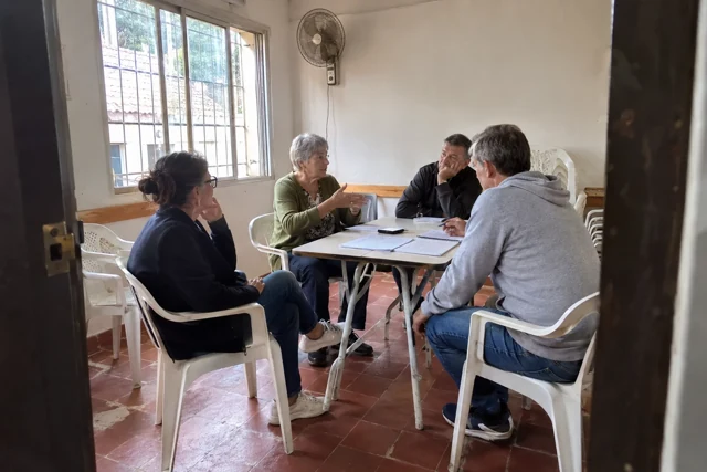 Vecinos reunidos en una sala común sencilla para decidir las funciones prioritarias.
